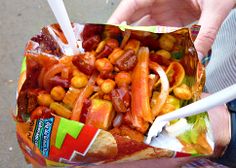 TOSTILOCOS recipe: cut bag of Tostilocos brand chips lengthwise, top with diced cucumber, diced jicama, diced tomatoes, Japanese peanuts, chaca-chaca candy, cueritos (pickled pork rinds), Valentina brand hot sauce and Chamoy. There you have some delicious Mexican street food.