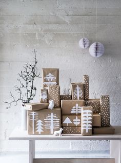 Christmas presents are wrapped with brown kraft paper. Decorations are made from white paper cut into tree shapes. Glue the paper trees onto the package. White paint pens create the &quot;snowfall&quot; design.