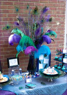 centerpiece with various sizes and colors of ostrich plumes and peacock feathers displayed in a vase filled with colored water and gemstones