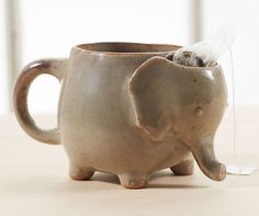A handmade stoneware tea mug shaped like a cute little elephant with a handy compartment to stash a tea bag after brewing.